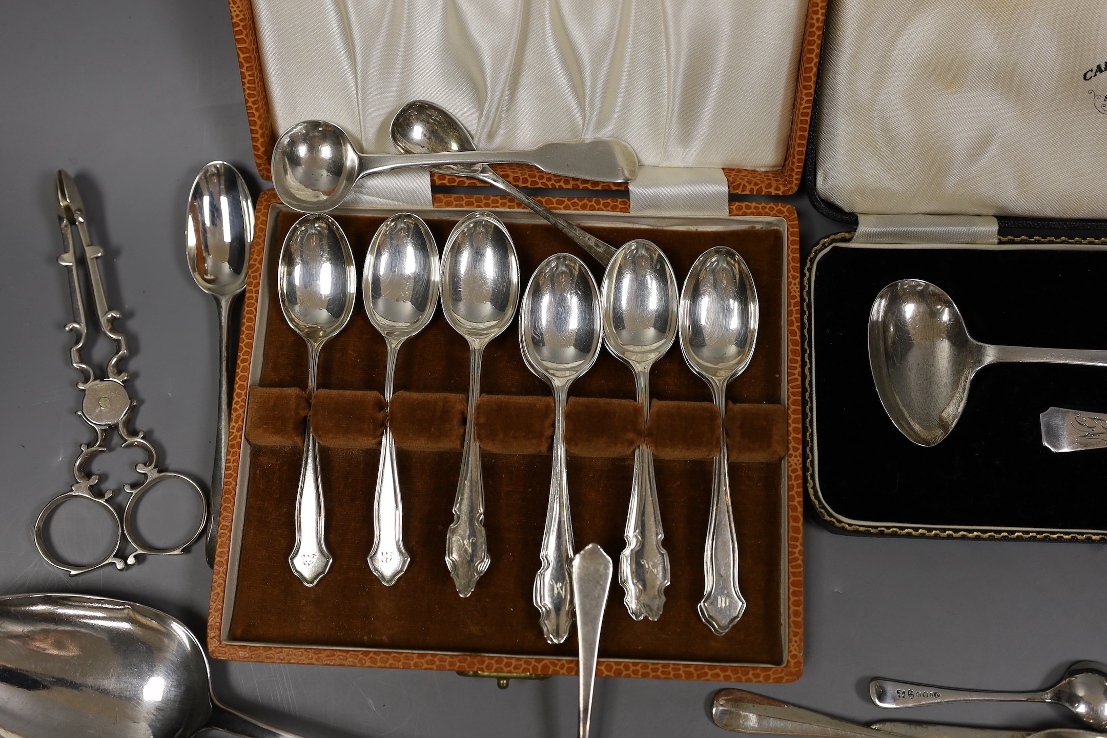 An Edwardian repousse silver oval dish, Birmingham, 1904, 22.8cm, a small quantity of assorted silver flatware including 18th and 19th century pairs of sugar nips, an 18th century silver toddy ladle, white metal cream ju